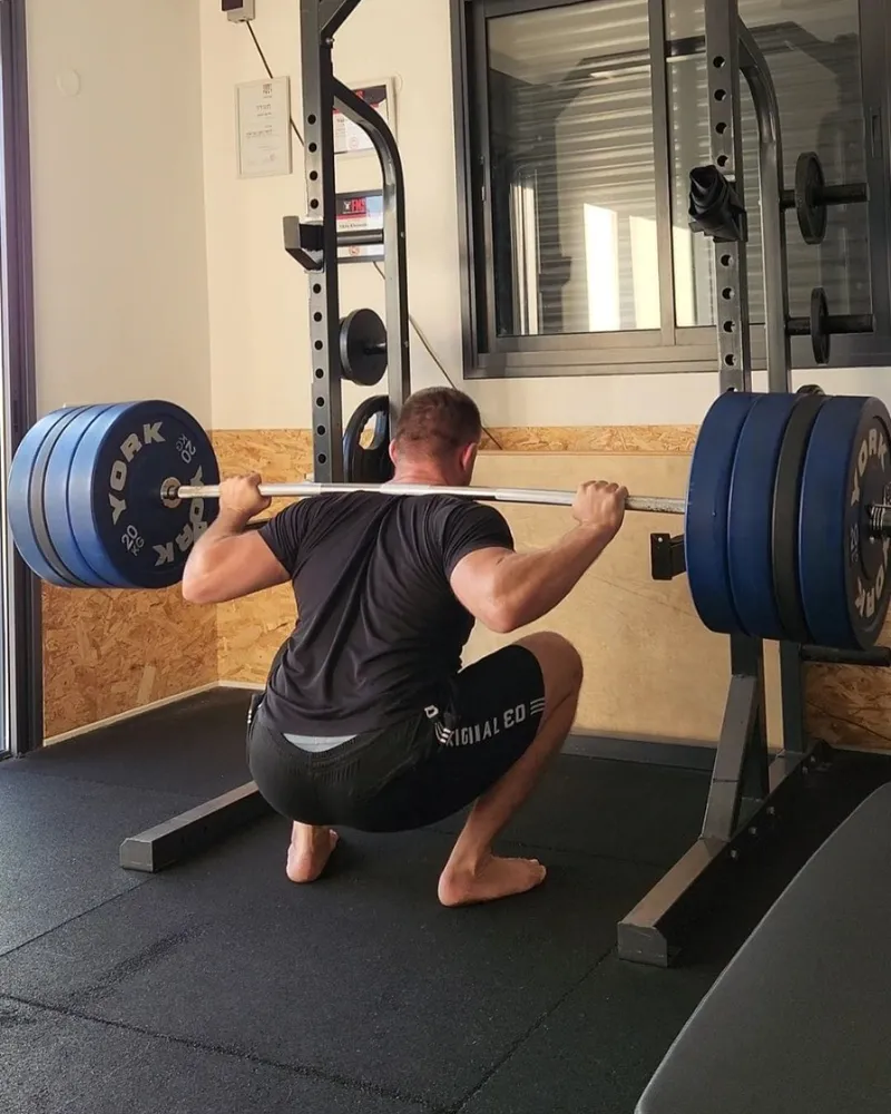 ניקיטה חומנקו מבצע סקוואט עם משקל כבד לפיתוח כוח מירבי